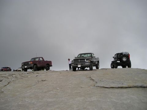 1989 Ford Bronco - A group of off-road vehicles are parked on a rocky outcrop, with a few people standing nearby.