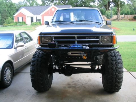 1986 Ford F-150 - This modified Toyota pickup truck features a prominent winch and oversized tires, suggesting off-road capability. The front grille clearly…