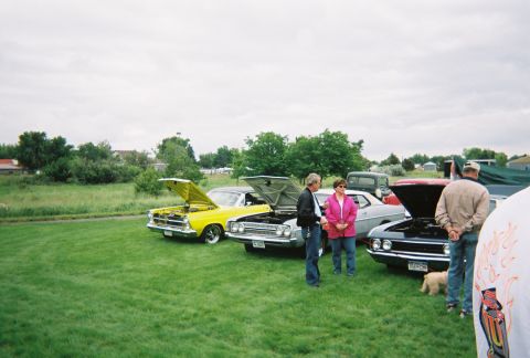 1972 Ford Ranchero - People gather around classic cars displayed outdoors on a cloudy day.