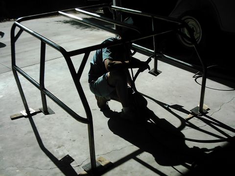 1978 Ford Bronco - A person works on installing a custom roll cage, with a partial vehicle visible in the background.