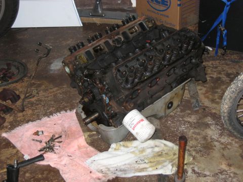 1985 Ford Crown Victoria LTD - A V8 engine sits on a garage floor, surrounded by tools and rags.