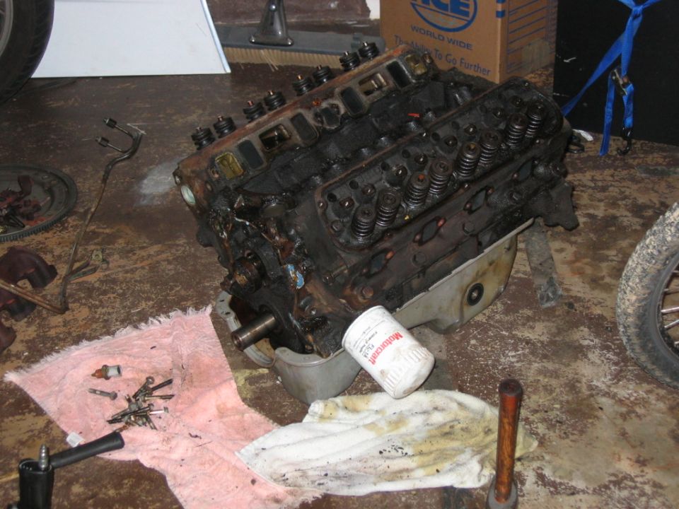 Dirty V8 engine block with a Motorcraft oil filter resting on the oil pan