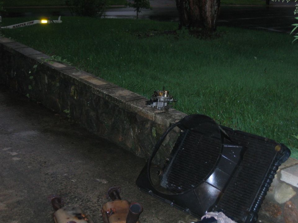 Carburetor, radiator, and mufflers on a stone wall and pavement