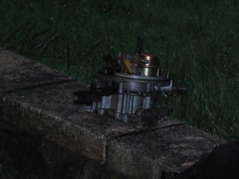 1985 Ford Crown Victoria LTD - A carburetor sits on a stone ledge with grass in the background.