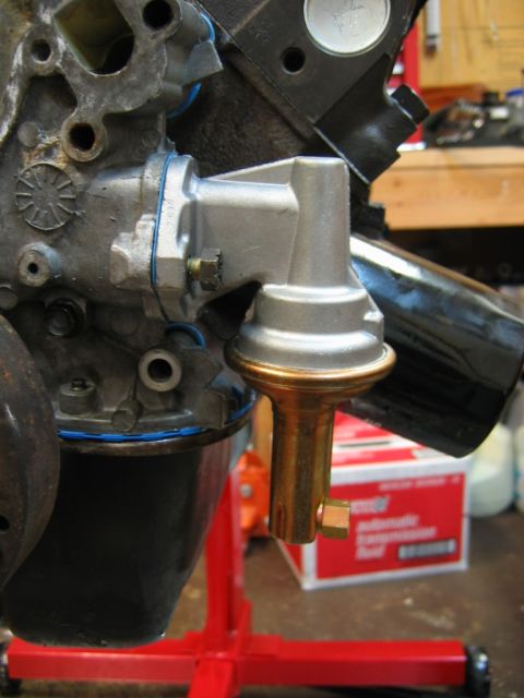 1985 Ford Crown Victoria LTD - Close-up of an engine block with a newly installed fuel pump, with a red engine stand supporting it.