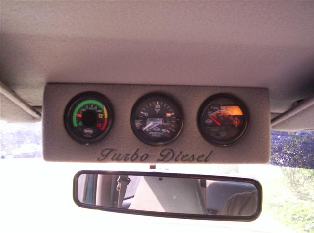 Three gauges mounted on the headliner, labeled 'Turbo Diesel'. One gauge shows RPM, another manifold pressure, and the third is illuminated