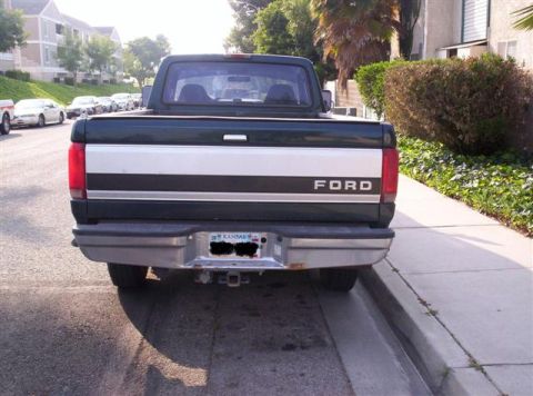 1995 Ford F-250 - Rear view of a dark green Ford pickup truck parked on a residential street.