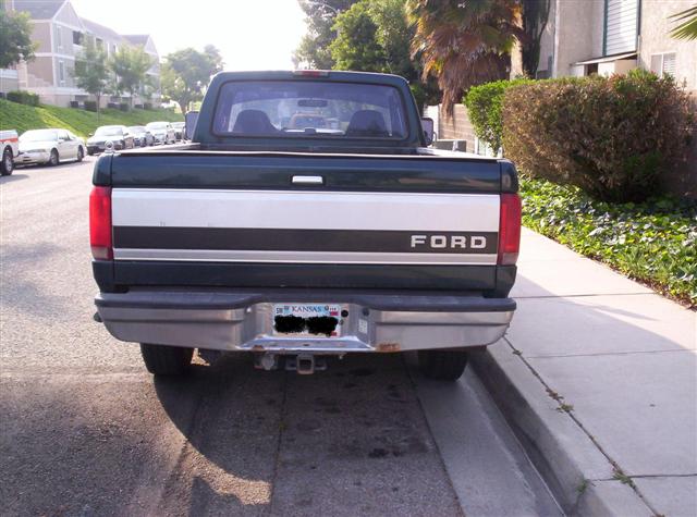 Dark green Ford pickup truck, rear view, with a silver stripe and 'FORD' lettering