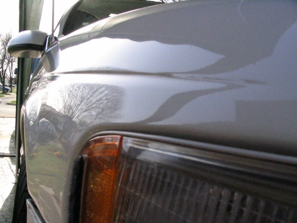 Silver car fender and headlight assembly, close-up side view