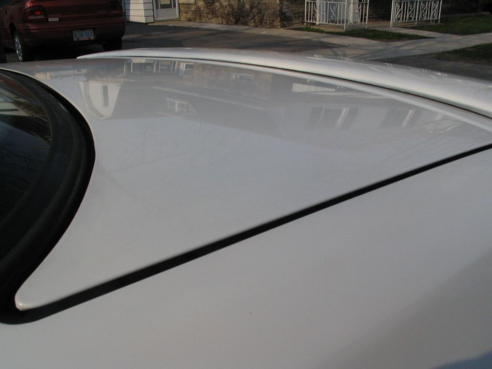 White car roof with reflections, red car in background