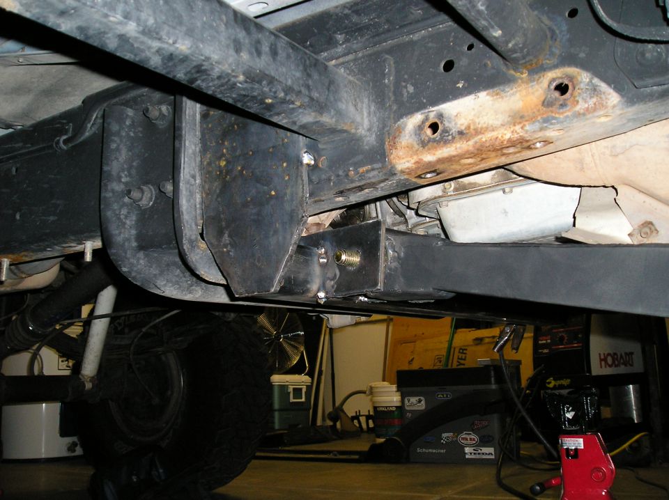 Underbody frame with welded bracket and rusty crossmember, garage tools in background