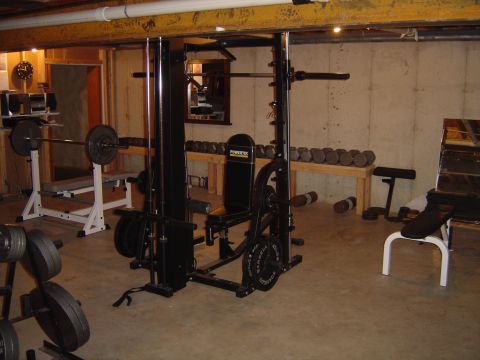 1978 Ford Bronco - A collection of weightlifting equipment is arranged in a basement gym area.