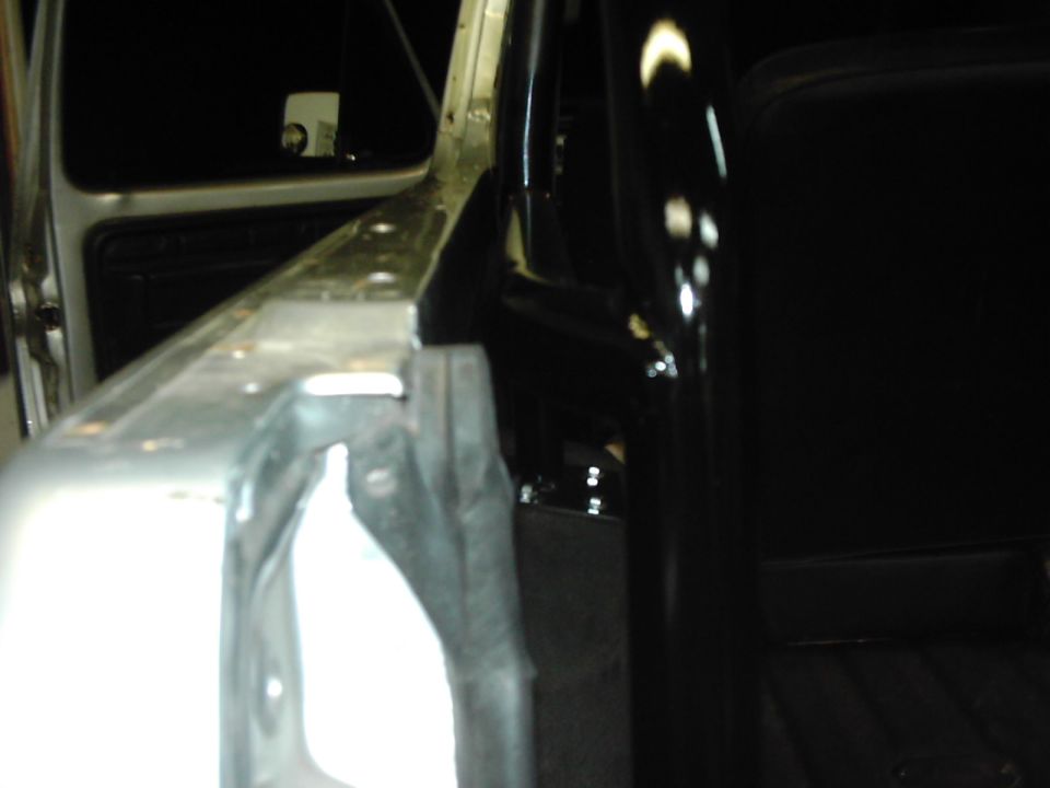 Interior of a vehicle showing a roll cage and door frame