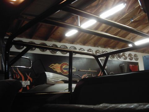 1978 Ford Bronco - Custom roll cage installed inside a vehicle, with hubcaps visible on the wall behind.