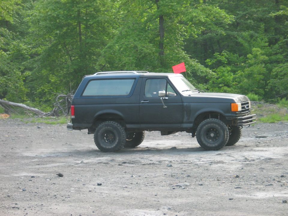 Black Ford Bronco with aftermarket wheels and tires parked on a gravel lot