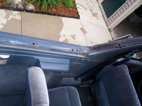 1986 Ford Bronco - The interior of a blue vehicle shows cloth seats and the frame where the top was removed.