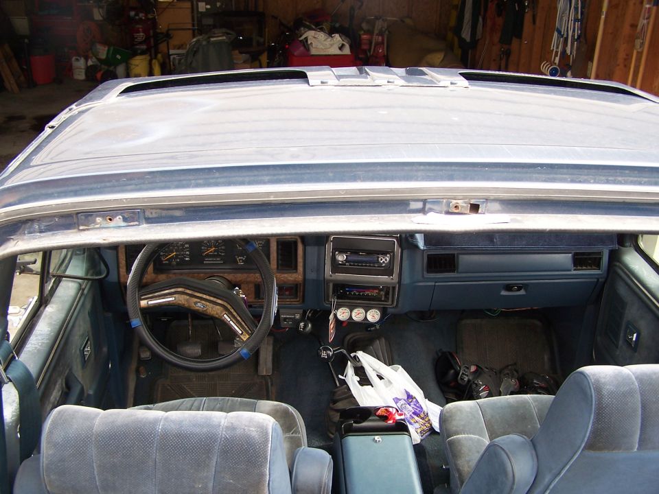 Top-down view into a blue Ford SUV interior with top removed, showing dash, gauges and bucket seats