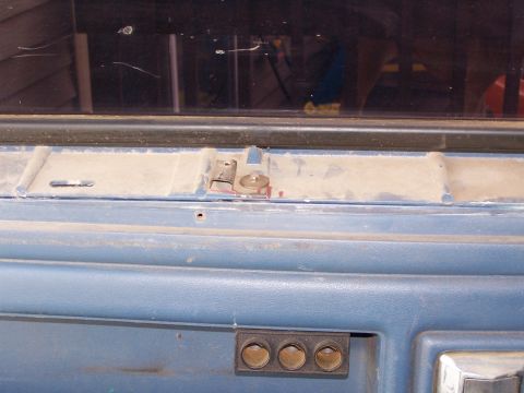 1986 Ford Bronco - Close-up of a vehicle's interior panel, showing a latch mechanism and control buttons.