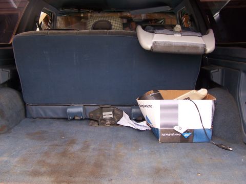 1986 Ford Bronco - The cargo area of the vehicle contains a box with Georgia-Pacific branding and some miscellaneous items.