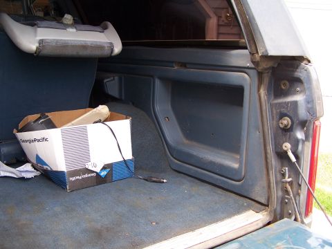 1986 Ford Bronco - Interior view of a vehicle's cargo area, showing blue carpeting and a box of supplies.