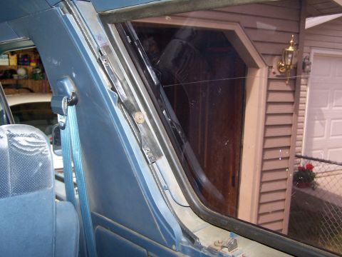 1986 Ford Bronco - Interior view of a vehicle's window mechanism and blue seatbelt.