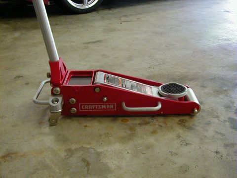 1994 Ford Probe - A red Craftsman floor jack is positioned on a concrete surface, with a portion of a car wheel visible in the upper left corner.