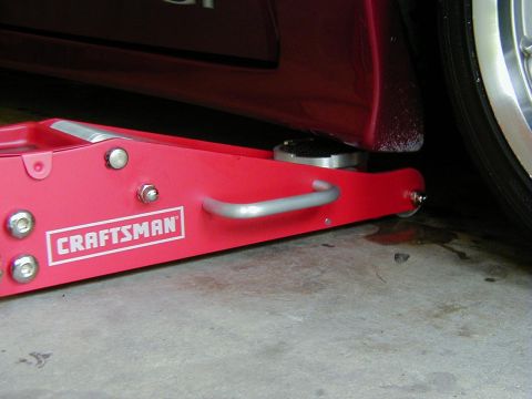 1994 Ford Probe - A red car jack is positioned under the side of a red vehicle.