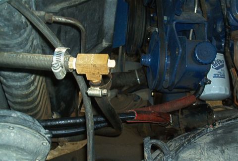 1986 Ford Bronco - Close-up view of engine bay components including hoses, a blue pump, and an oil filter.