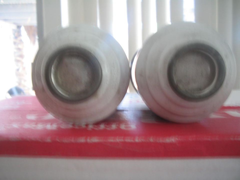 Two white polyurethane bushing sleeves standing on a red box in bright window light