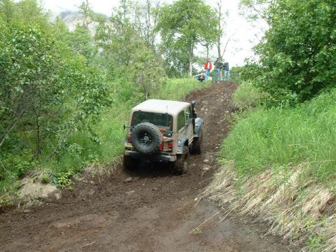 2000 Jeep Wrangler - A Jeep Wrangler navigates a steep, muddy trail during an off-road event.