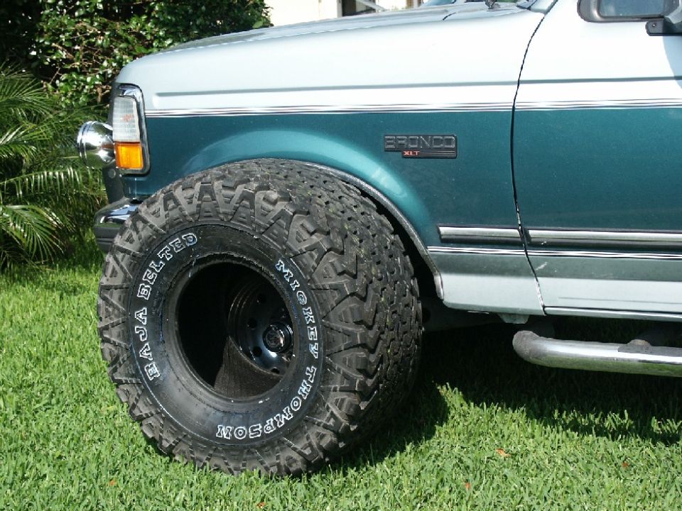 Front fender of teal/white Bronco XLT with large Mickey Thompson Baja Belted tire on black wheel