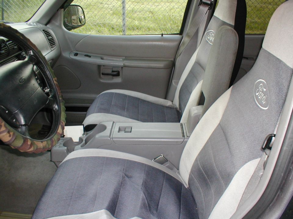 Interior view of a car showing front seats, center console, and steering wheel with camouflage cover
