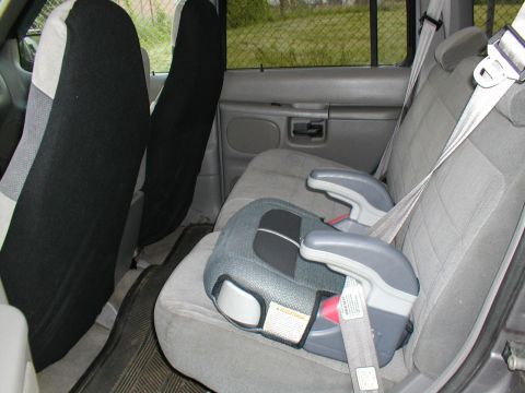1979 Ford Bronco - The interior of a vehicle is visible, with a car seat installed on the rear bench seat.