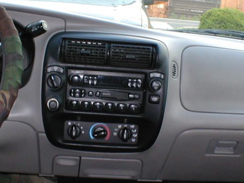 1979 Ford Bronco - The interior dashboard features the radio and climate controls, with a camouflage-patterned steering wheel cover visible.