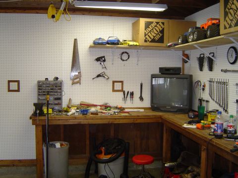 1989 Ford Bronco - A cluttered workbench in a garage, with tools, a vintage television, and various storage solutions.