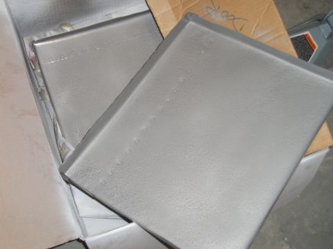 1996 Ford Bronco - Gray plastic interior panels are shown inside a cardboard box, with text visible on a piece of cardboard in the background.