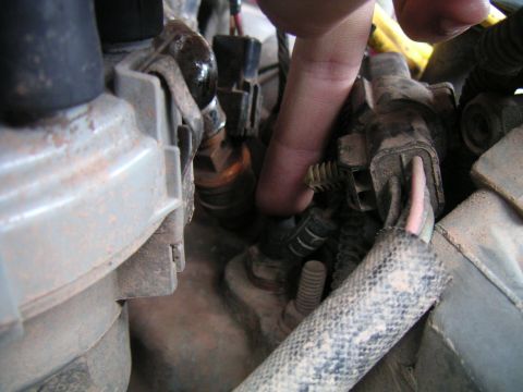 1994 Ford Bronco - A finger points to a sensor connector amidst a tangle of wires and engine parts.