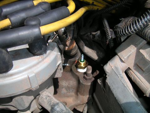 1994 Ford Bronco - A new temperature sensor is installed in the engine block, surrounded by various engine components and wiring.