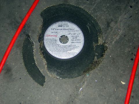 1995 Ford Bronco - A 14-inch cut-off wheel for metal is shown on a concrete surface with debris.