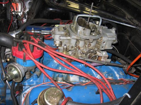 1972 Ford Mustang - Engine bay detail a carburetor and distributor with red spark plug wires.