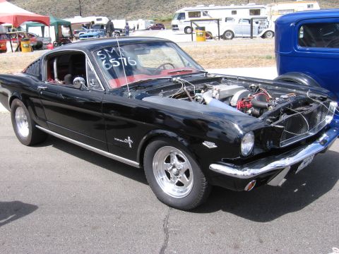 1972 Ford Mustang - A black 1965 Ford Mustang fastback is parked with its hood open, revealing the engine bay.