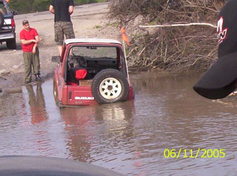 1995 Ford Bronco - Red Suzuki Samurai stuck in water with people around on 06/11/2005.