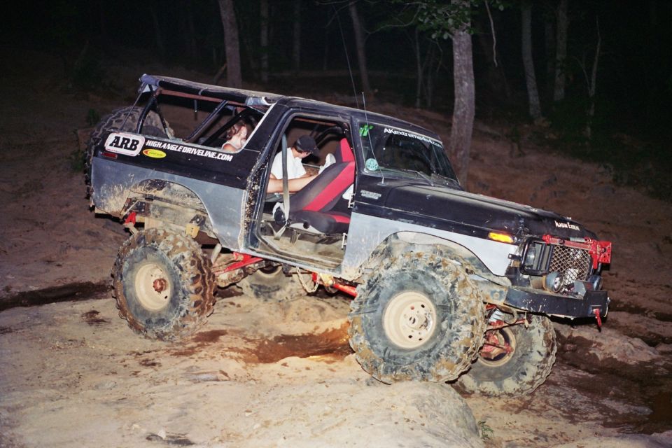Modified SUV with large tires on a dirt trail at night. ARB sticker on the side