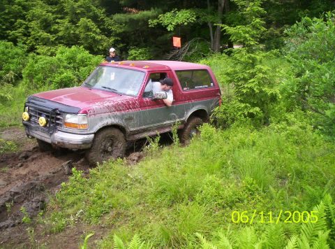1995 Ford Bronco - A lifted maroon and silver two-tone full-size Bronco with a brush guard, yellow-lens driving lights, roof-mounted lamp pods and mud-caked m…