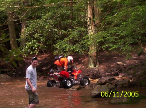1995 Ford Bronco - Two people and a red ATV are in a stream surrounded by trees.