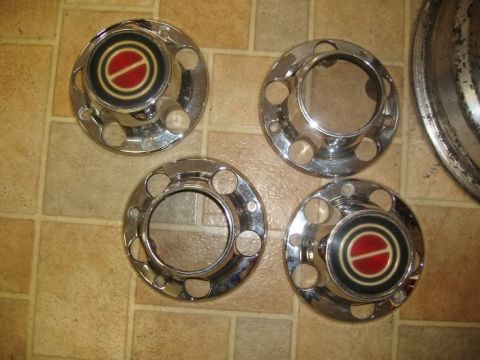 1994 Ford Bronco - Set of four chrome hubcaps, two with red and black emblems, on a tiled surface.