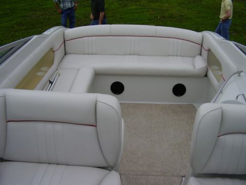 1997 Crownline 266 CCR - The interior of a boat shows white seating with red piping and two black speaker grilles.