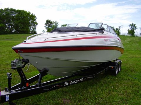 1997 Crownline 266 CCR - A white and red boat is parked on a trailer in a grassy area.