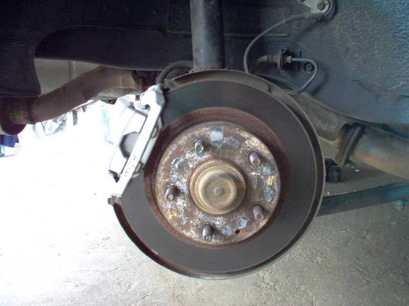 Rear brake rotor and caliper assembly with exhaust pipe visible