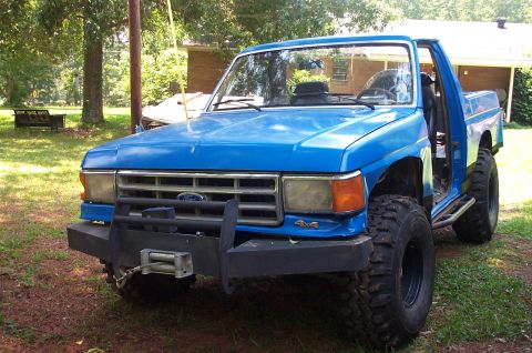 1987 Ford Bronco - This blue pickup truck features a winch and large tires, suggesting it's modified for off-road use.
